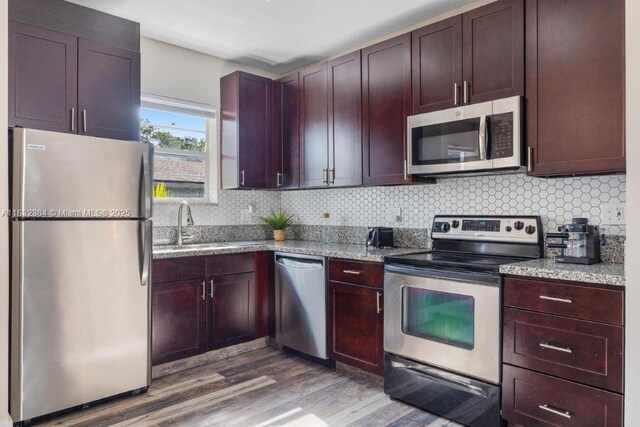 505 SE 20th St, Fort Lauderdale, FL 33316 - kitchen featuring stainless steel appliances, wood finished floors, backsplash, and light stone counters