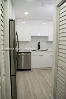 976 N 18th Ct, Hollywood, FL 33020 - kitchen featuring dishwasher, white cabinets, light wood finished floors, modern cabinets, and light countertops