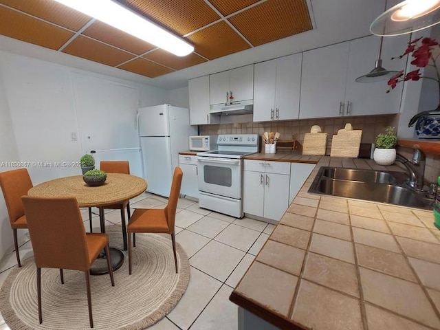 1351 NE Miami Gardens Dr Unit 513E, Miami, FL 33179 - kitchen featuring white appliances, tile counters, under cabinet range hood, decorative backsplash, and white cabinetry