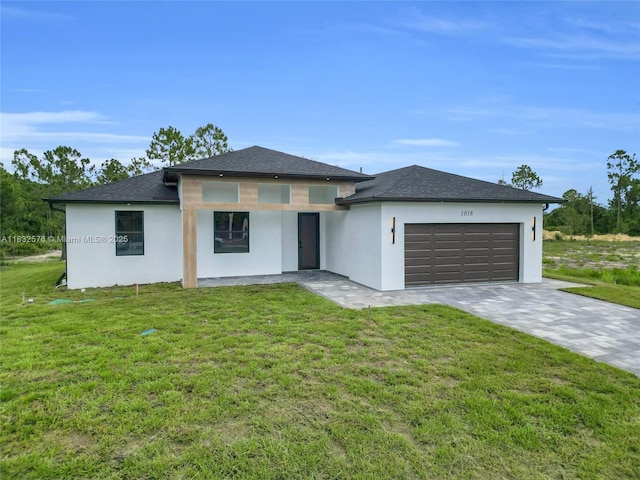 1018 Calvin Ave, Lehigh Acres, FL 33972 - prairie-style house with stucco siding, a garage, a front lawn, driveway, and roof with shingles