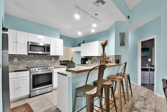1419 Avon Ln Unit 216, North Lauderdale, FL 33068 - kitchen featuring stainless steel appliances, white cabinetry, a peninsula, a kitchen bar, and backsplash