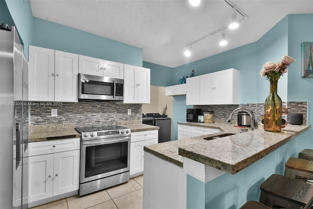 1419 Avon Ln Unit 216, North Lauderdale, FL 33068 - kitchen featuring appliances with stainless steel finishes, separate washer and dryer, a peninsula, light stone countertops, and backsplash