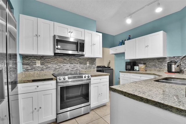 1419 Avon Ln Unit 216, North Lauderdale, FL 33068 - kitchen featuring appliances with stainless steel finishes, separate washer and dryer, light stone counters, white cabinetry, and a textured ceiling