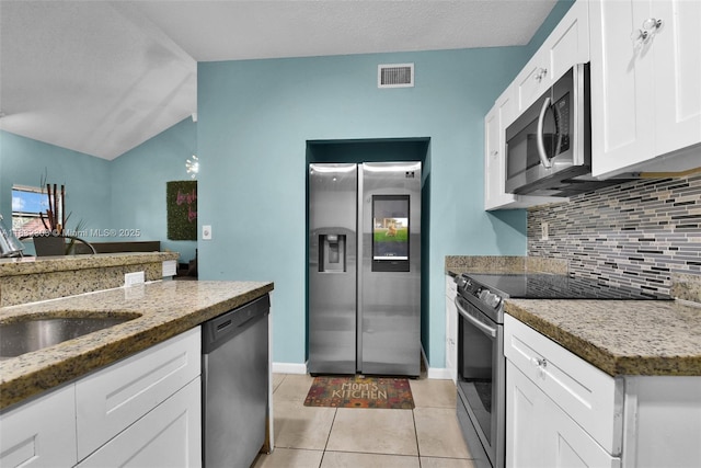 1419 Avon Ln Unit 216, North Lauderdale, FL 33068 - kitchen with stainless steel appliances, decorative backsplash, white cabinets, light tile patterned floors, and vaulted ceiling