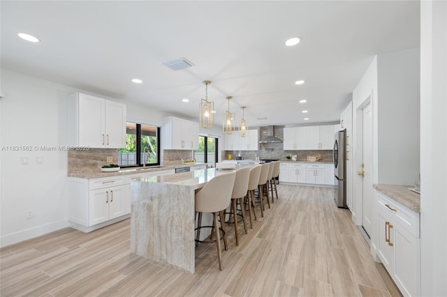 10704 SW 133rd Ter, Miami, FL 33176 - kitchen featuring freestanding refrigerator, a breakfast bar, a kitchen island, wall chimney range hood, and tasteful backsplash