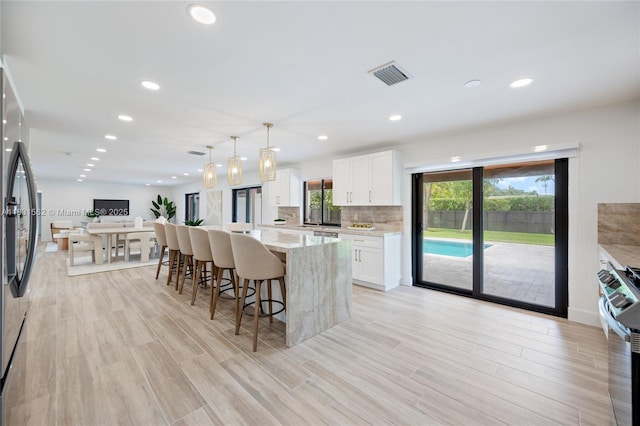 10704 SW 133rd Ter, Miami, FL 33176 - kitchen featuring stove, a kitchen bar, white cabinetry, tasteful backsplash, and light wood finished floors