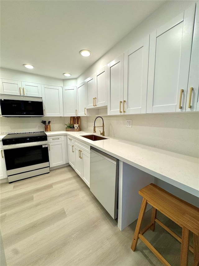 300 Bayview Dr Unit 1801, Sunny Isles Beach, FL 33160 - kitchen featuring white appliances, white cabinetry, light wood finished floors, and recessed lighting