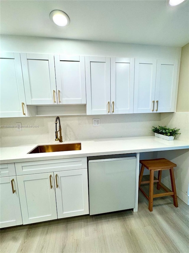 300 Bayview Dr Unit 1801, Sunny Isles Beach, FL 33160 - kitchen with dishwashing machine, light wood-type flooring, light countertops, white cabinets, and a kitchen bar