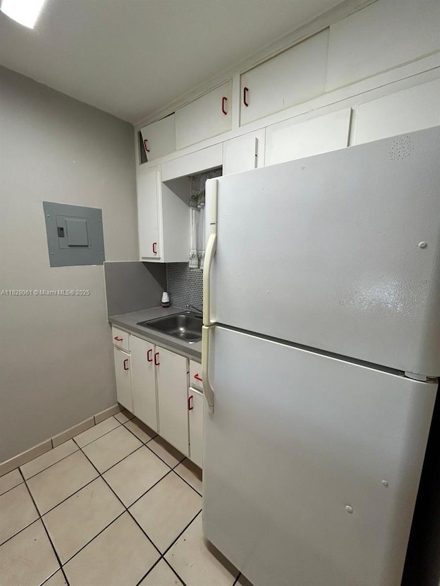 3181 SW 13th St Unit 401, Miami, FL 33145 - kitchen featuring freestanding refrigerator, electric panel, white cabinetry, and light tile patterned flooring