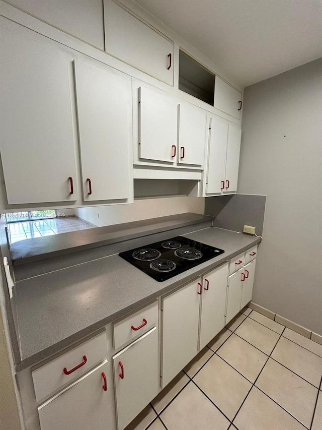 3181 SW 13th St Unit 401, Miami, FL 33145 - kitchen with black electric stovetop, white cabinetry, light tile patterned flooring, under cabinet range hood, and dark countertops