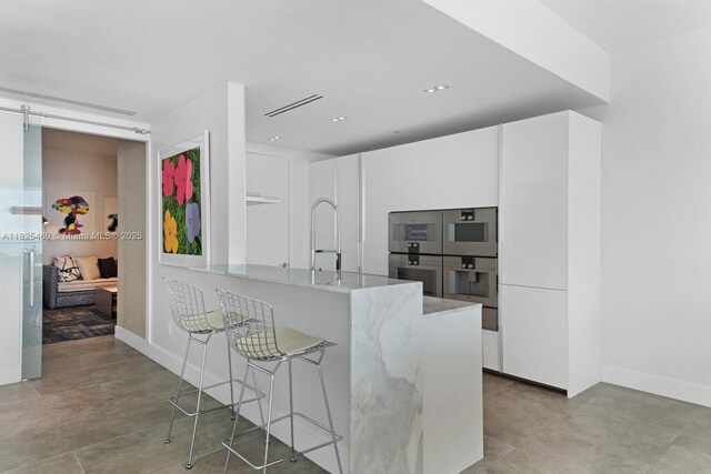 10203 Collins Ave Unit 1003, Bal Harbour, FL 33154 - kitchen with light stone counters, double oven, and white cabinets