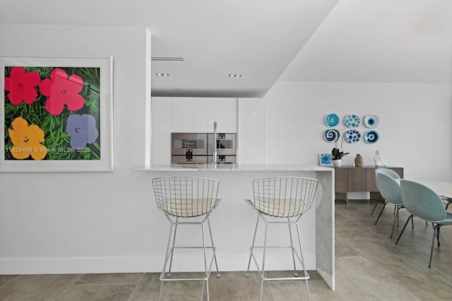 10203 Collins Ave Unit 1003, Bal Harbour, FL 33154 - kitchen featuring white cabinetry, a kitchen bar, light countertops, a peninsula, and modern cabinets