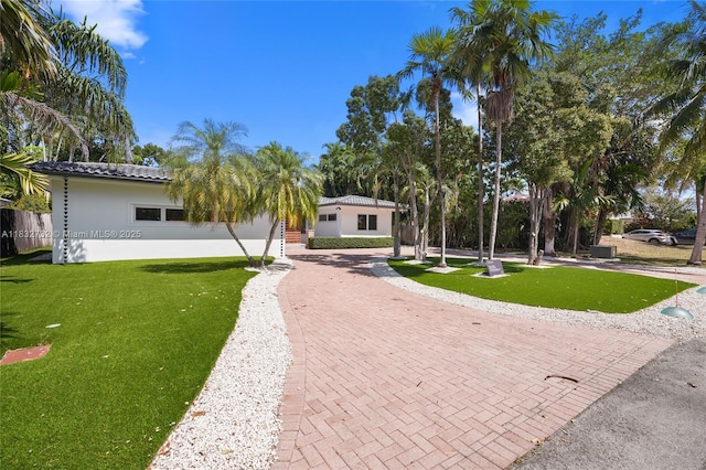 1221 NE 87th St, Miami, FL 33138 - view of front of property with decorative driveway, a front yard, stucco siding, and a tile roof