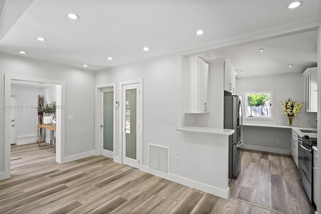 1221 NE 87th St, Miami, FL 33138 - kitchen with appliances with stainless steel finishes, light countertops, white cabinets, light wood finished floors, and recessed lighting
