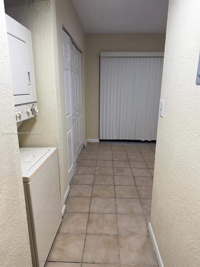 2341 W 66th Pl Unit 103, Hialeah, FL 33016 - washroom featuring stacked washing machine and dryer, light tile patterned floors, and a textured wall