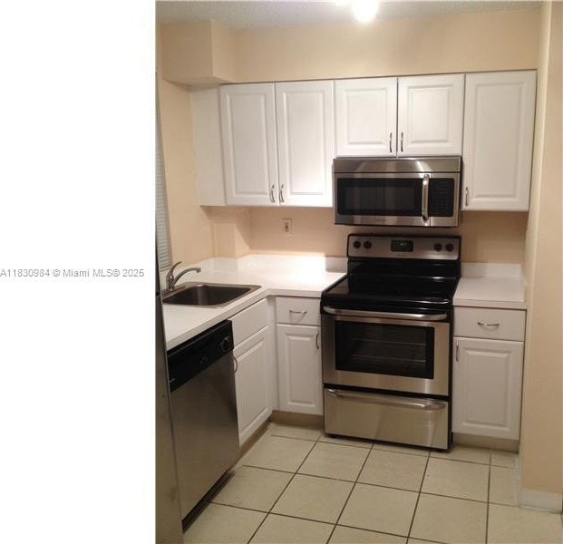 6045 NW 186th St Unit 103, Hialeah, FL 33015 - kitchen with stainless steel appliances, white cabinets, and light tile patterned floors