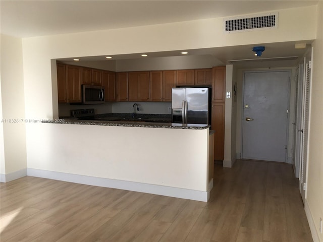 5700 Collins Ave Unit 6J, Miami Beach, FL 33140 - kitchen with stainless steel appliances, light wood-style floors, a peninsula, recessed lighting, and dark stone counters