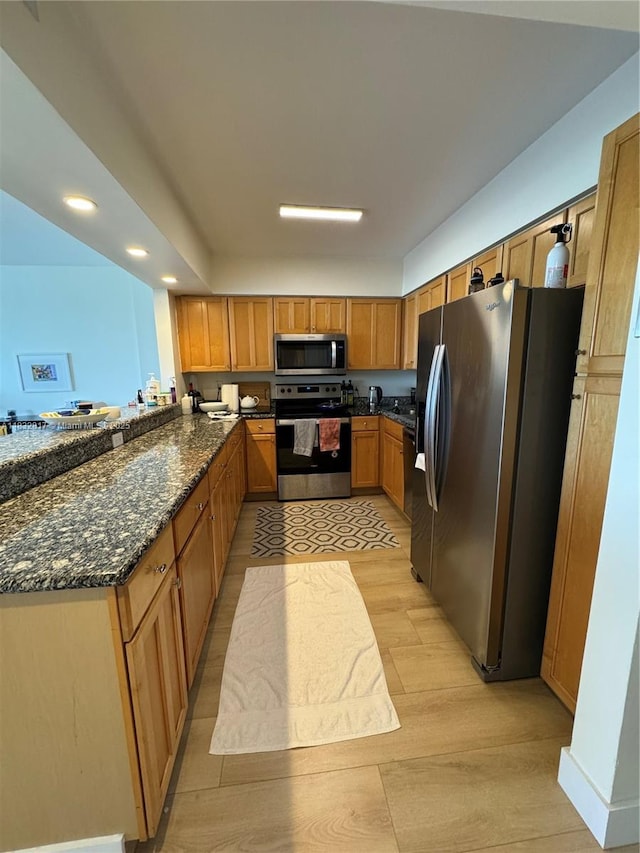 5700 Collins Ave Unit 6J, Miami Beach, FL 33140 - kitchen featuring stainless steel appliances, light wood-type flooring, dark stone countertops, brown cabinetry, and recessed lighting