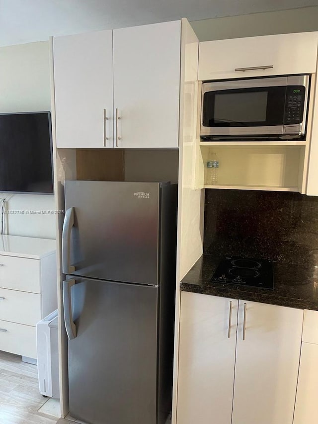 19201 Collins Ave Unit 717, Sunny Isles Beach, FL 33160 - kitchen with stainless steel appliances, white cabinetry, dark stone counters, modern cabinets, and light wood-style flooring
