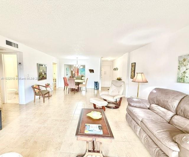 200 178th Dr Unit 409, Sunny Isles Beach, FL 33160 - living room featuring a textured ceiling, light tile patterned floors, and a chandelier