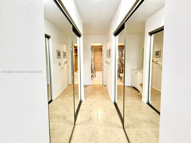 200 178th Dr Unit 409, Sunny Isles Beach, FL 33160 - hall featuring a textured ceiling and light tile patterned flooring