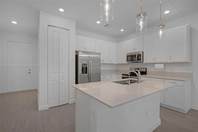 14549 Bretton Woods Trce, Delray Beach, FL 33446 - kitchen with stainless steel appliances, light wood finished floors, white cabinetry, hanging light fixtures, and a center island with sink
