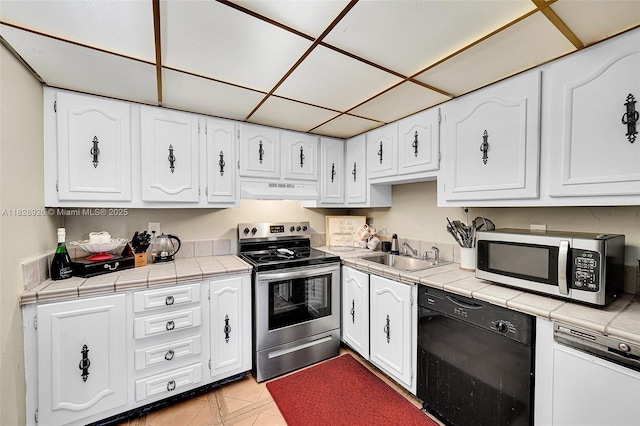 470 N Laurel Dr Unit 3A, Margate, FL 33063 - kitchen with appliances with stainless steel finishes, white cabinetry, tile counters, under cabinet range hood, and light tile patterned floors