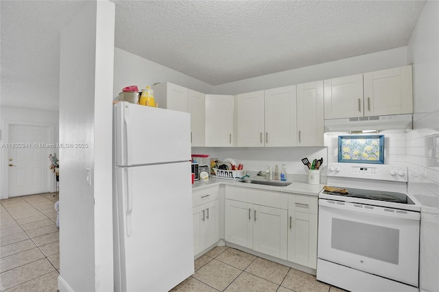1200 W 31st St, Riviera Beach, FL 33404 - kitchen with white appliances, a textured ceiling, light tile patterned floors, white cabinets, and under cabinet range hood