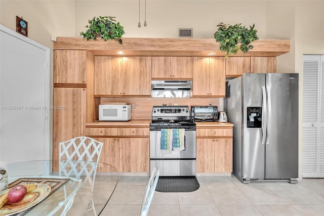 631 SW 113th Ave, Pembroke Pines, FL 33025 - kitchen featuring stainless steel appliances, under cabinet range hood, light countertops, light tile patterned floors, and light brown cabinets