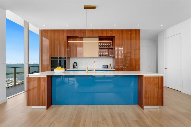 2655 S Bayshore Dr Unit 2012, Miami, FL 33133 - kitchen featuring modern cabinets, brown cabinetry, tasteful backsplash, light countertops, and a wall of windows