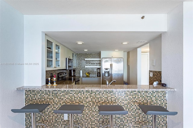 555 NE 15th St Unit 15B, Miami, FL 33132 - kitchen with stainless steel appliances, decorative backsplash, glass insert cabinets, a peninsula, and stone counters