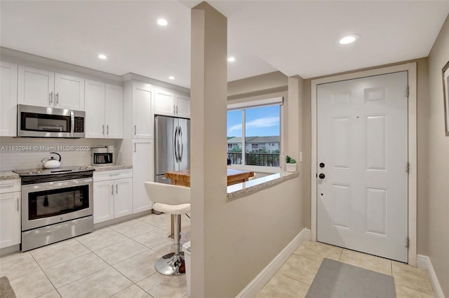 800 SW 125th Way Unit 405O, Pembroke Pines, FL 33027 - kitchen featuring stainless steel appliances, white cabinets, light tile patterned floors, decorative backsplash, and recessed lighting
