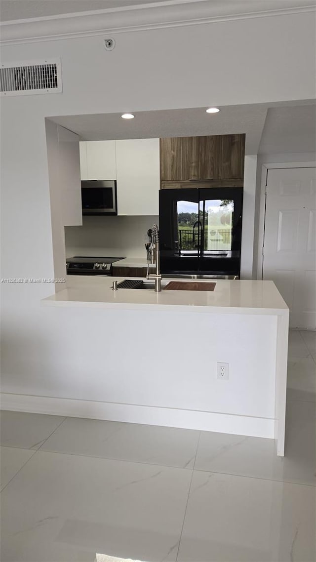 230 SW 117th Ter, Pembroke Pines, FL 33025 - kitchen featuring appliances with stainless steel finishes, white cabinets, modern cabinets, light countertops, and a peninsula