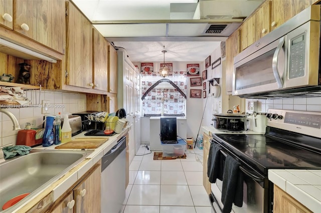 3070 NW 48th Ter Unit 415, Lauderdale Lakes, FL 33313 - kitchen featuring stainless steel appliances, tile countertops, decorative backsplash, and light tile patterned floors