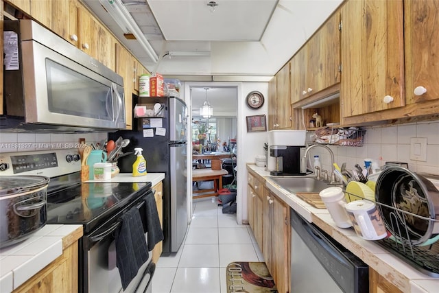 3070 NW 48th Ter Unit 415, Lauderdale Lakes, FL 33313 - kitchen with appliances with stainless steel finishes, tile counters, light tile patterned floors, decorative backsplash, and brown cabinetry