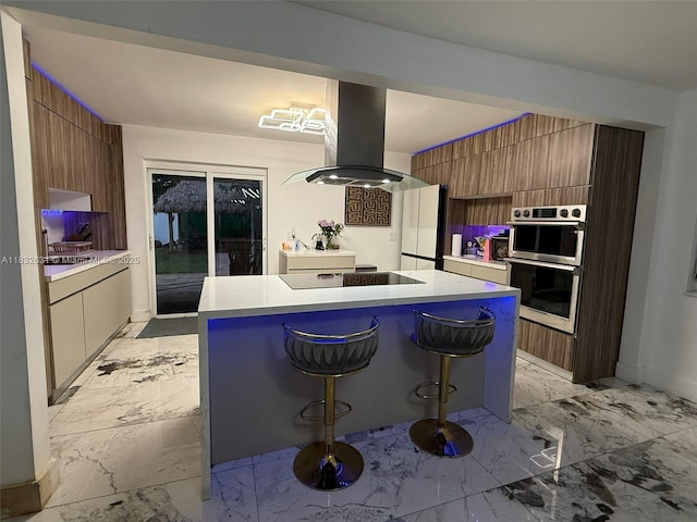 5838 Madison St, Hollywood, FL 33023 - kitchen with island exhaust hood, stainless steel double oven, light marble finish flooring, freestanding refrigerator, and light countertops