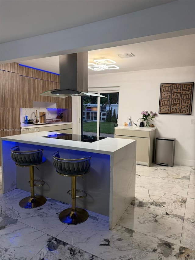 5838 Madison St, Hollywood, FL 33023 - kitchen with island range hood, light marble finish floors, a kitchen breakfast bar, light countertops, and brown cabinetry