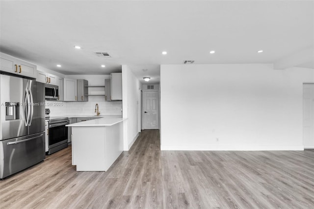 6117 NW 9th St, Margate, FL 33063 - kitchen with stainless steel appliances, open shelves, gray cabinets, a peninsula, and light countertops