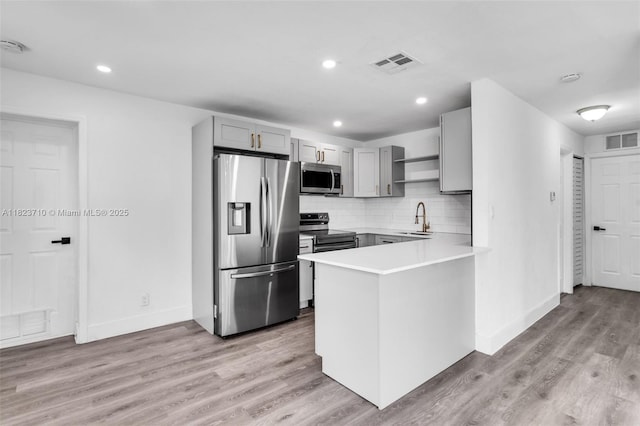 6117 NW 9th St, Margate, FL 33063 - kitchen with appliances with stainless steel finishes, open shelves, gray cabinetry, a peninsula, and light countertops
