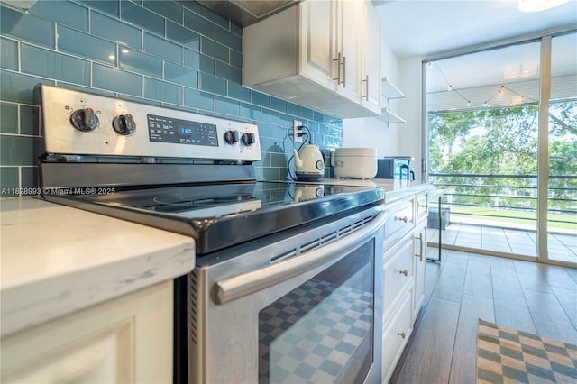 kitchen featuring stainless steel range with electric cooktop, backsplash, light countertops, and wood-type flooring
