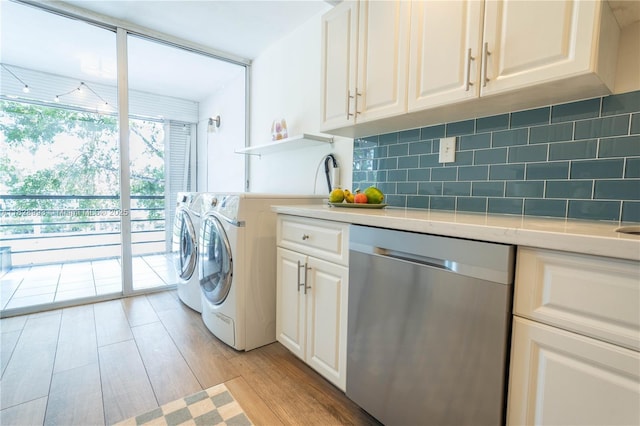 laundry room featuring independent washer and dryer, cabinet space, and light wood-type flooring