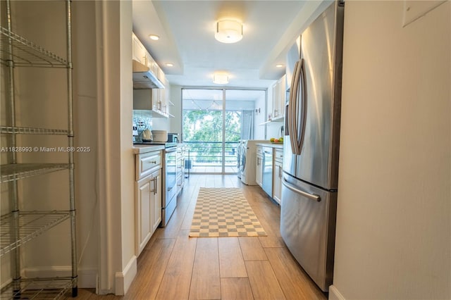 kitchen with stainless steel appliances, washer / dryer, light wood-type flooring, white cabinets, and recessed lighting