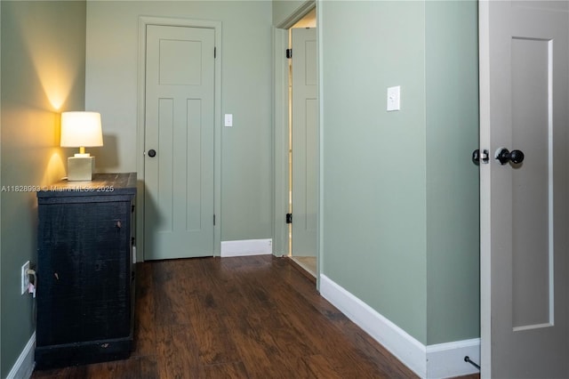 corridor featuring baseboards and dark wood finished floors