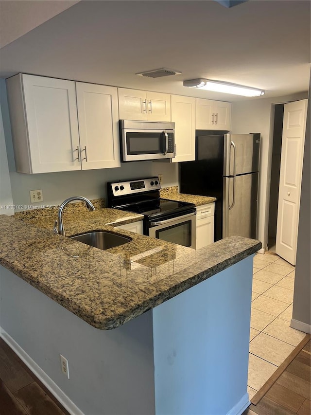 10725 Cleary Blvd Unit 205, Plantation, FL 33324 - kitchen with appliances with stainless steel finishes, a peninsula, dark stone countertops, white cabinets, and light tile patterned flooring