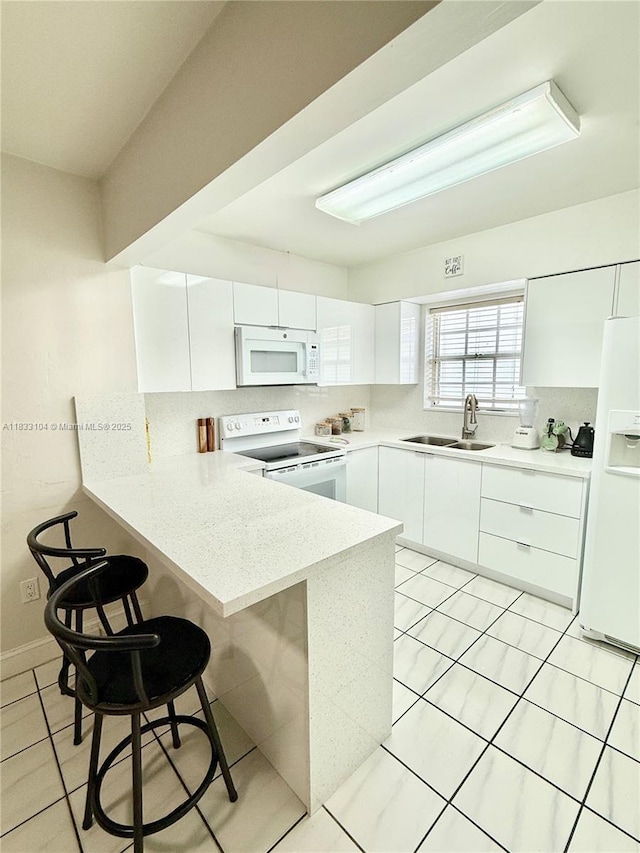 2145 SW 26th St, Miami, FL 33133 - kitchen featuring white appliances, a peninsula, a breakfast bar area, white cabinets, and modern cabinets