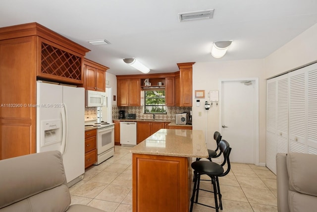 15471 SW 83rd Ave, Palmetto Bay, FL 33157 - kitchen with white appliances, decorative backsplash, light tile patterned floors, a breakfast bar area, and a kitchen island
