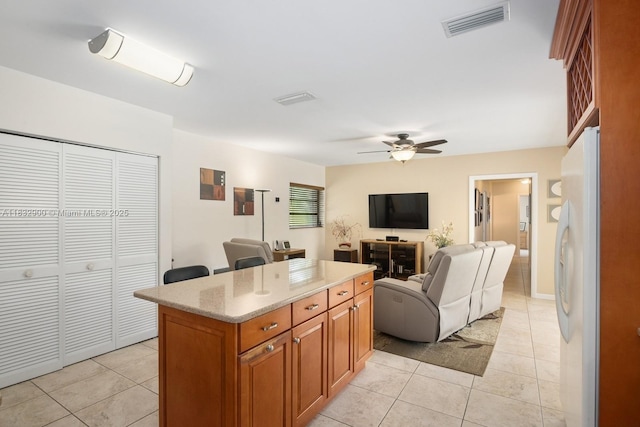 15471 SW 83rd Ave, Palmetto Bay, FL 33157 - kitchen featuring freestanding refrigerator, light tile patterned floors, brown cabinetry, a ceiling fan, and a center island