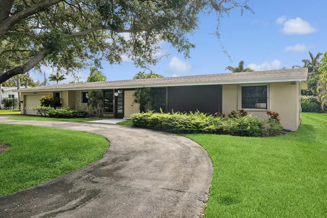 15471 SW 83rd Ave, Palmetto Bay, FL 33157 - ranch-style house with curved driveway, stucco siding, a front lawn, and an attached garage