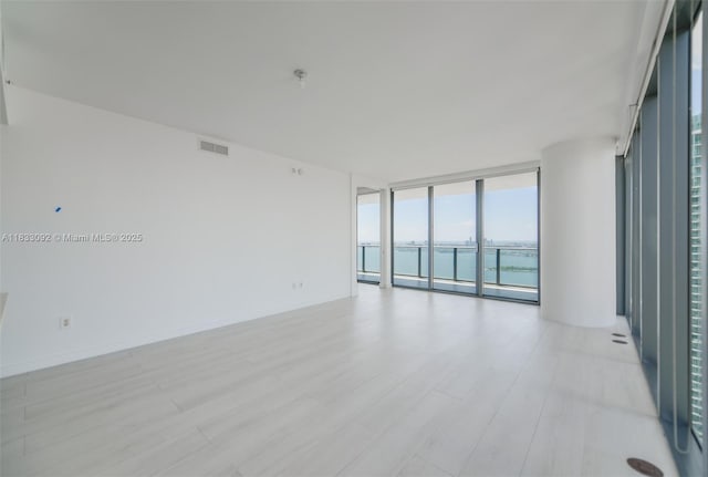 650 NE 32nd St Unit 4301, Miami, FL 33137 - unfurnished room featuring a wall of windows, a water view, and light wood-style flooring