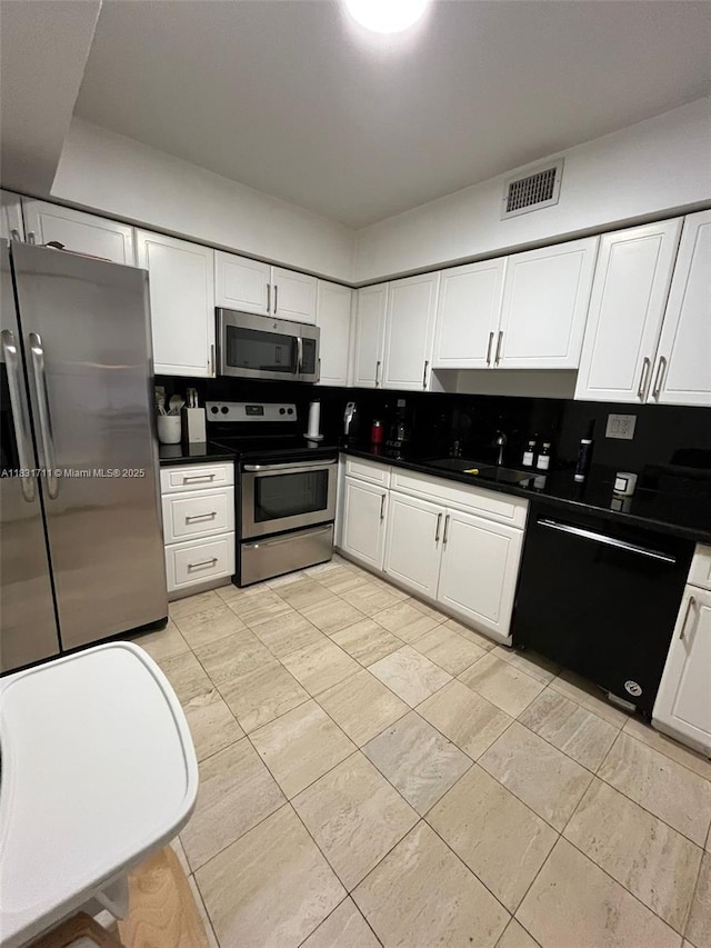 3600 NE Mystic Pointe Dr Unit 1010, Aventura, FL 33180 - kitchen featuring stainless steel appliances, white cabinetry, dark countertops, and light tile patterned floors